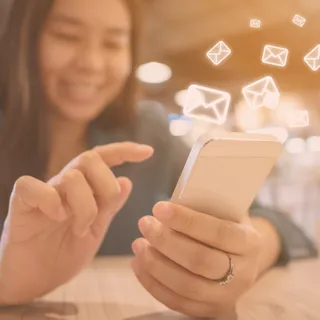 A woman points her hand at her phone with email icons