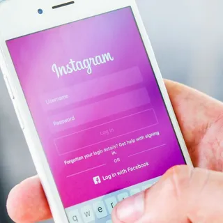 A hand holds a cell phone open to the Instagram login page