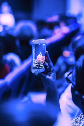 A hand holds a phone above a crowd at an event