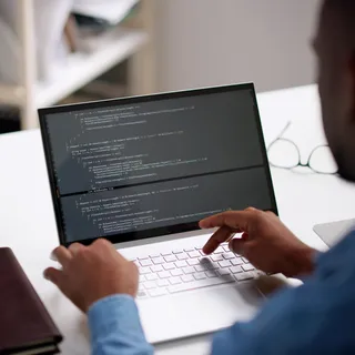 A website developer types on a laptop computer