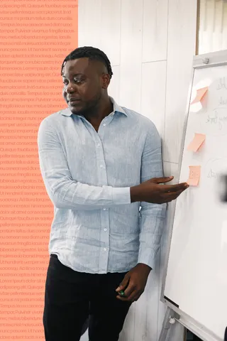 A meeting facilitator points to sticky notes on a board