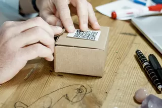 Hand places QR code sticker on a small box