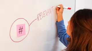 Woman writes the word "relevant" on a white board