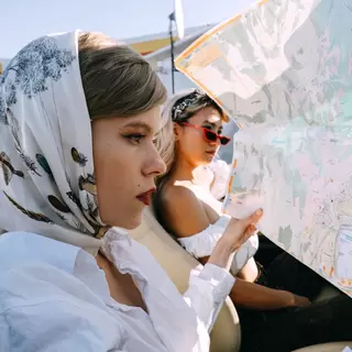 Two women in a car reading a roadmap