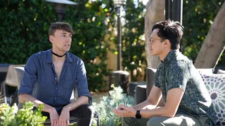 Two young professionals face one another sitting on an outdoor patio