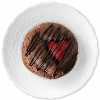 A chocolate cookie with a strawberry covered in chocolate drizzle